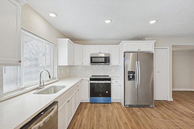 kitchen featuring stainless steel appliances, white cabinetry, tasteful backsplash, and sink