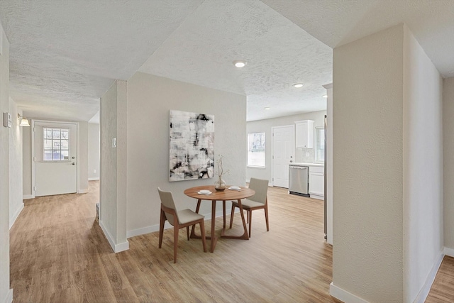 hall with plenty of natural light, a textured ceiling, and light hardwood / wood-style flooring