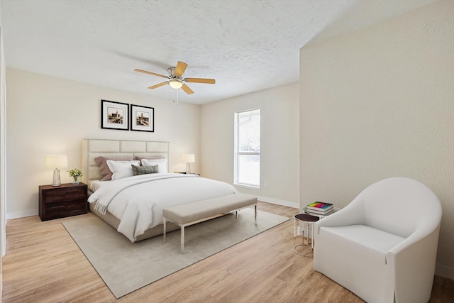 bedroom with ceiling fan, a textured ceiling, and light wood-type flooring