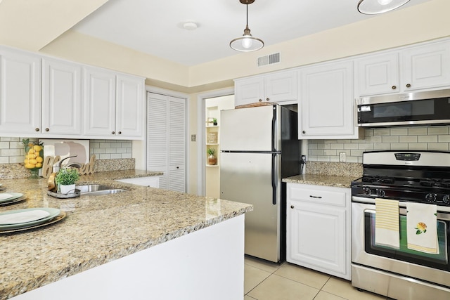 kitchen with decorative light fixtures, white cabinets, light tile patterned floors, and stainless steel appliances