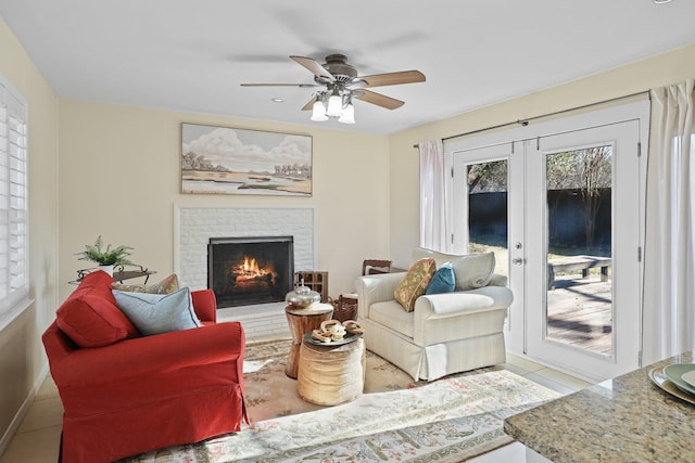 tiled living room featuring ceiling fan, french doors, and a brick fireplace