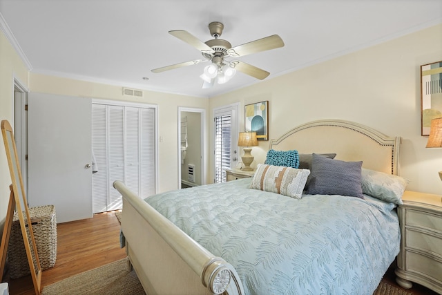 bedroom featuring hardwood / wood-style floors, a closet, ceiling fan, and ornamental molding