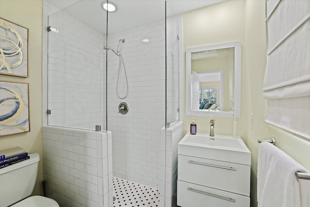 bathroom featuring tiled shower, toilet, and vanity