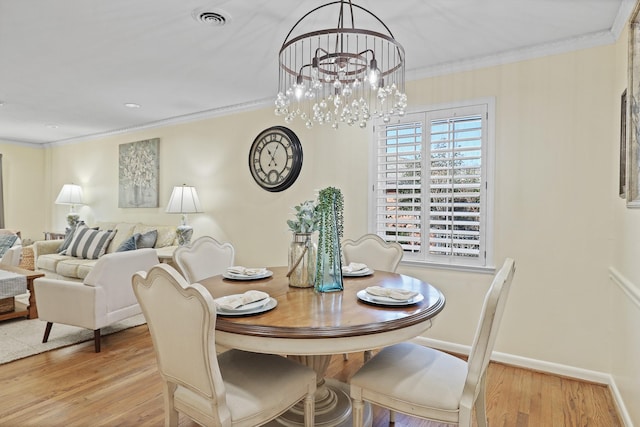 dining space with a notable chandelier, light wood-type flooring, and crown molding