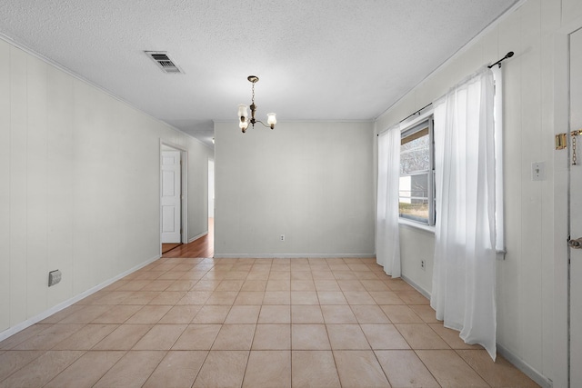 empty room featuring light tile patterned floors, a textured ceiling, and a chandelier