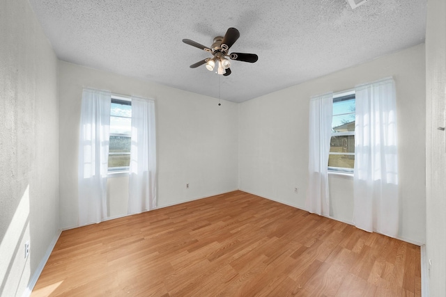 spare room with ceiling fan, light hardwood / wood-style flooring, and a textured ceiling