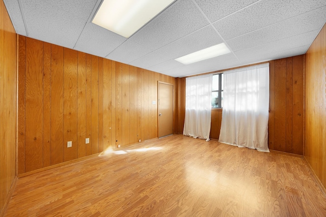 spare room featuring light hardwood / wood-style floors and wood walls