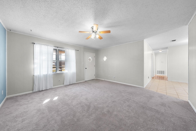 empty room featuring light carpet, ceiling fan, and a textured ceiling