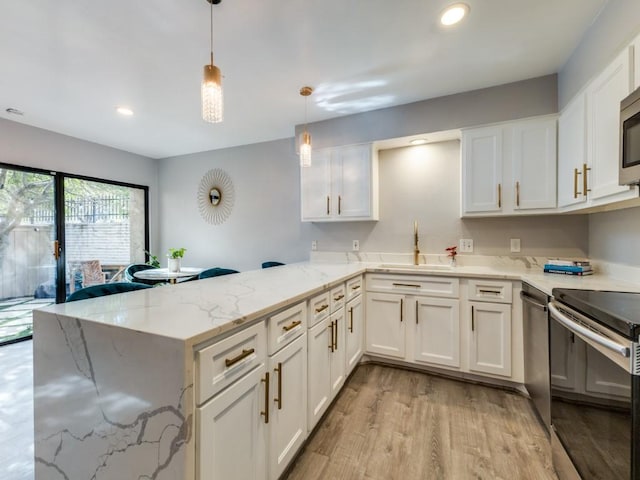 kitchen with sink, white cabinetry, stainless steel appliances, decorative light fixtures, and kitchen peninsula