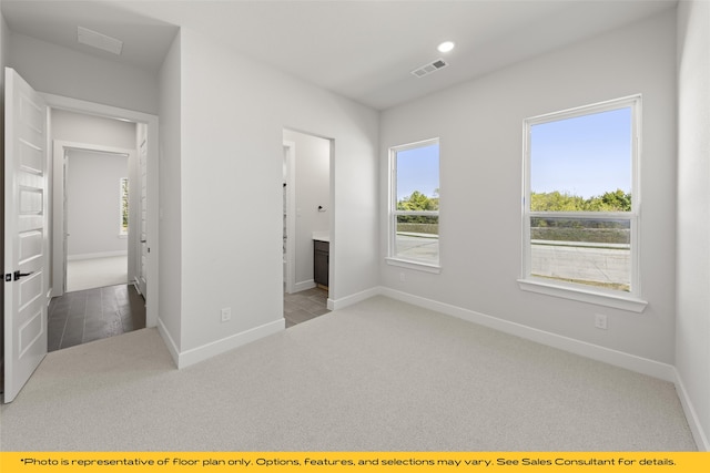 unfurnished bedroom featuring light colored carpet and ensuite bath