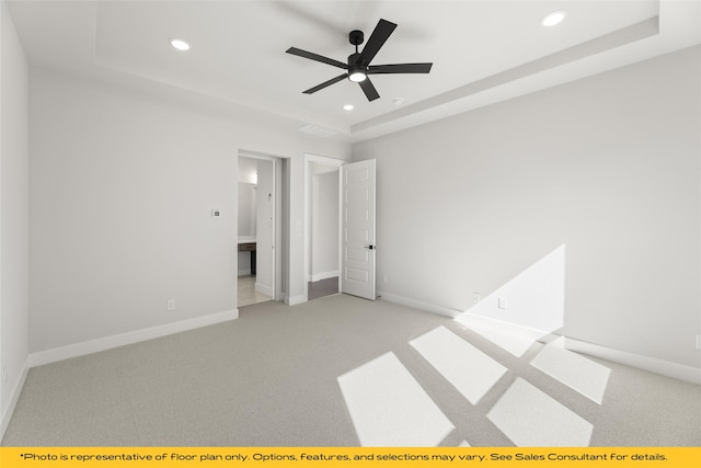 unfurnished bedroom with ceiling fan, light carpet, and a tray ceiling