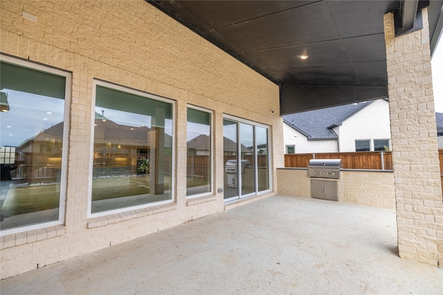 view of patio featuring an outdoor kitchen, a grill, and fence