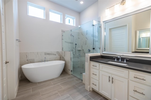 bathroom with vanity, tile walls, a freestanding tub, and a stall shower