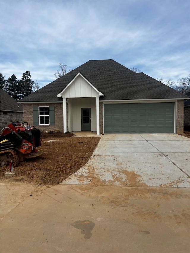 ranch-style home with driveway, a shingled roof, an attached garage, board and batten siding, and brick siding