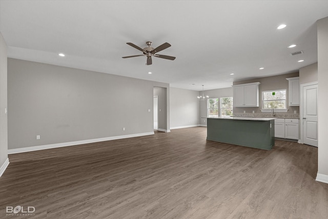 kitchen with a center island, dark wood finished floors, visible vents, open floor plan, and ceiling fan with notable chandelier