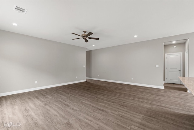 empty room featuring a ceiling fan, dark wood-style flooring, visible vents, and baseboards