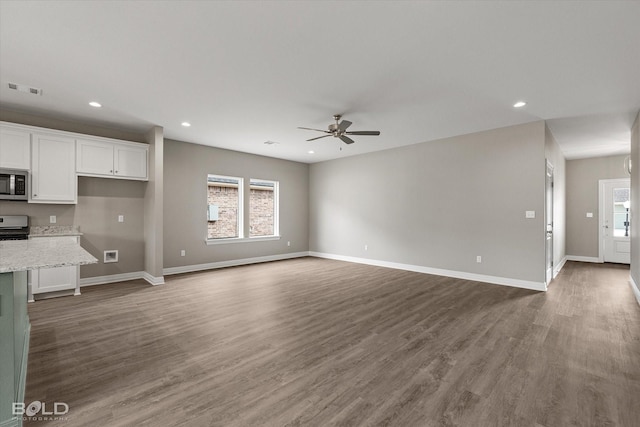 unfurnished living room with plenty of natural light, visible vents, and dark wood finished floors