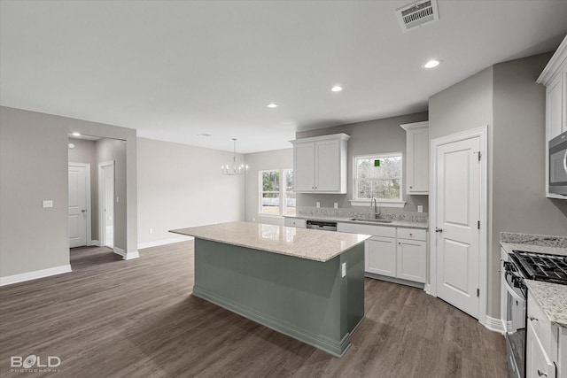 kitchen with appliances with stainless steel finishes, white cabinetry, a kitchen island, and dark wood-style floors