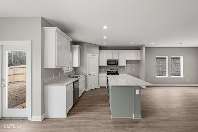 kitchen featuring stainless steel appliances, recessed lighting, light wood-style floors, white cabinets, and a sink