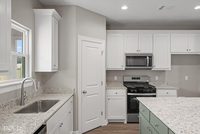 kitchen with appliances with stainless steel finishes, a sink, visible vents, and white cabinets