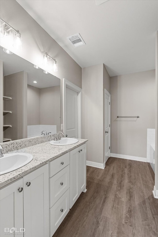 full bath featuring baseboards, visible vents, a sink, and wood finished floors