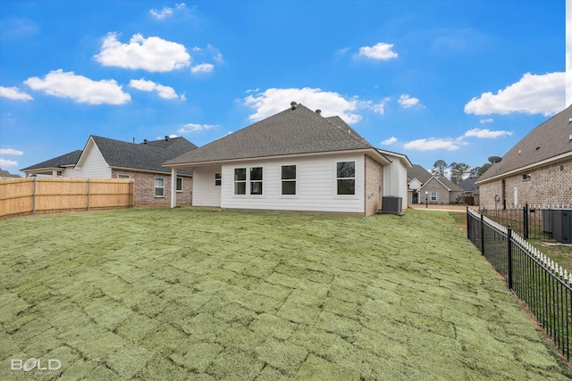 rear view of property featuring a yard, central AC unit, and fence private yard