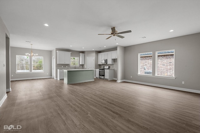 unfurnished living room with recessed lighting, dark wood finished floors, baseboards, and ceiling fan with notable chandelier