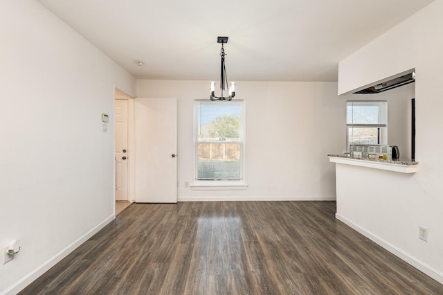 unfurnished dining area with a wealth of natural light, dark hardwood / wood-style flooring, and a notable chandelier