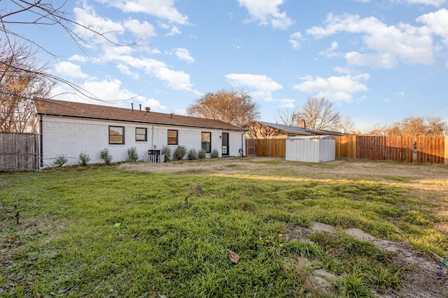 rear view of property featuring a storage shed and a lawn