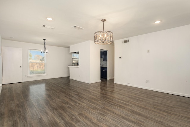 unfurnished living room with dark wood-type flooring and a notable chandelier