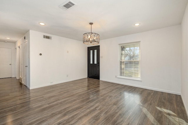 spare room featuring a chandelier and dark hardwood / wood-style floors