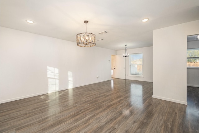 unfurnished living room with dark wood-type flooring and a chandelier