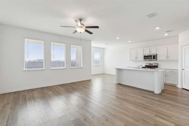 kitchen featuring appliances with stainless steel finishes, light hardwood / wood-style flooring, white cabinetry, and a wealth of natural light