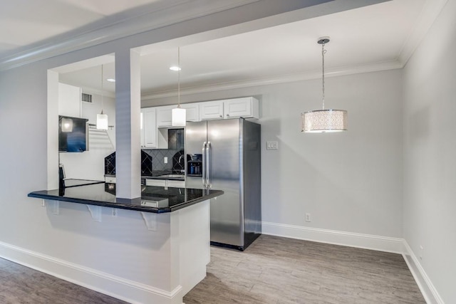 kitchen featuring stainless steel refrigerator with ice dispenser, kitchen peninsula, decorative light fixtures, decorative backsplash, and white cabinets