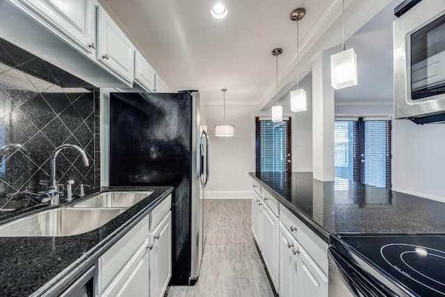 kitchen with dark stone countertops, sink, white cabinets, and decorative light fixtures