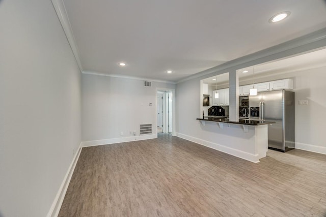 unfurnished living room with light wood-type flooring and ornamental molding