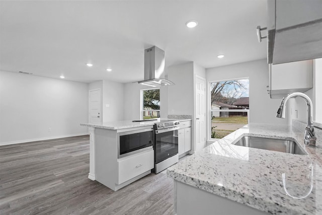 kitchen with stainless steel range with electric stovetop, island range hood, white cabinetry, and sink