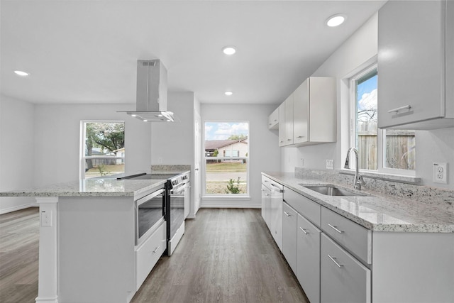 kitchen with island exhaust hood, electric range, sink, and white cabinets