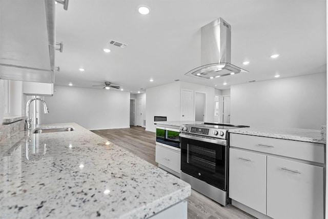 kitchen with island exhaust hood, white cabinetry, sink, and stainless steel electric range oven