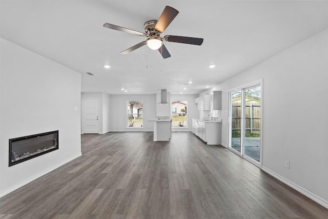 unfurnished living room with ceiling fan, dark hardwood / wood-style floors, sink, and a wealth of natural light