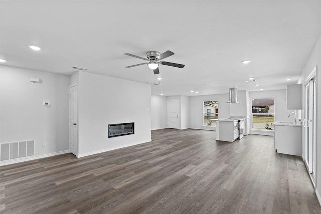 unfurnished living room featuring ceiling fan, sink, and dark wood-type flooring