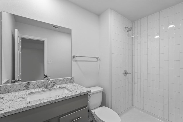 bathroom featuring vanity, toilet, and tiled shower