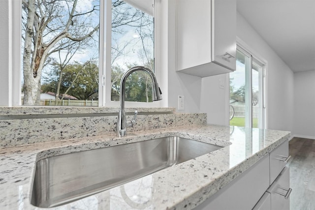 room details with light stone countertops, sink, and white cabinets