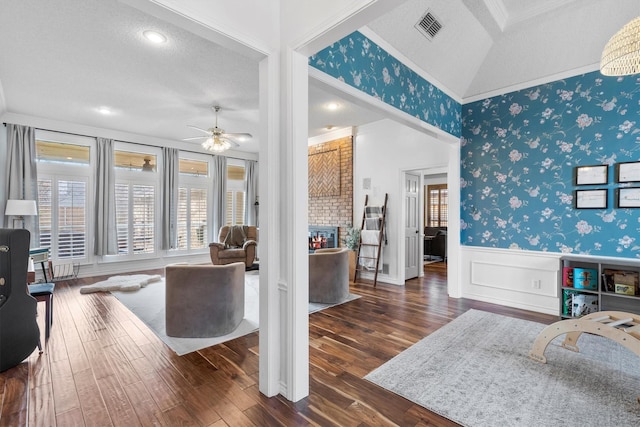 living room featuring ceiling fan, dark hardwood / wood-style flooring, crown molding, vaulted ceiling, and a fireplace