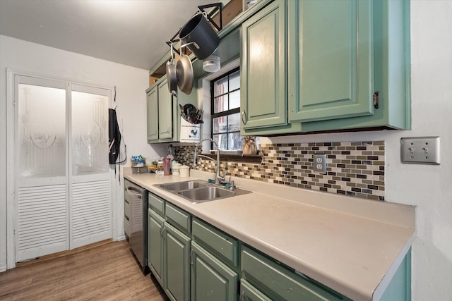 kitchen with backsplash, stainless steel dishwasher, sink, light hardwood / wood-style flooring, and green cabinets