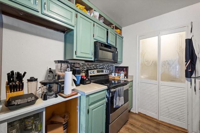 kitchen with tasteful backsplash, green cabinets, dark hardwood / wood-style floors, and stainless steel range with electric stovetop