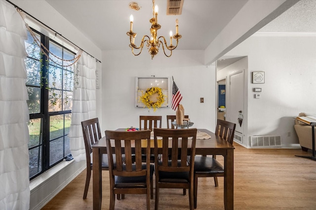 dining area featuring wood-type flooring, an inviting chandelier, plenty of natural light, and ornamental molding