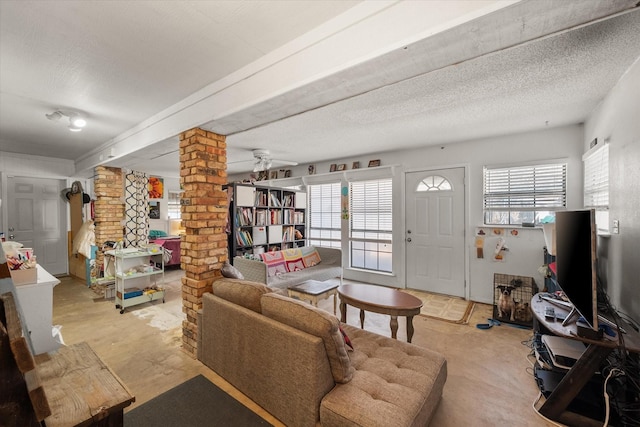 living room with a textured ceiling, ornate columns, plenty of natural light, and ceiling fan