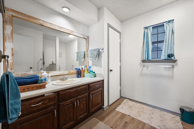 bathroom featuring hardwood / wood-style flooring, vanity, and a textured ceiling