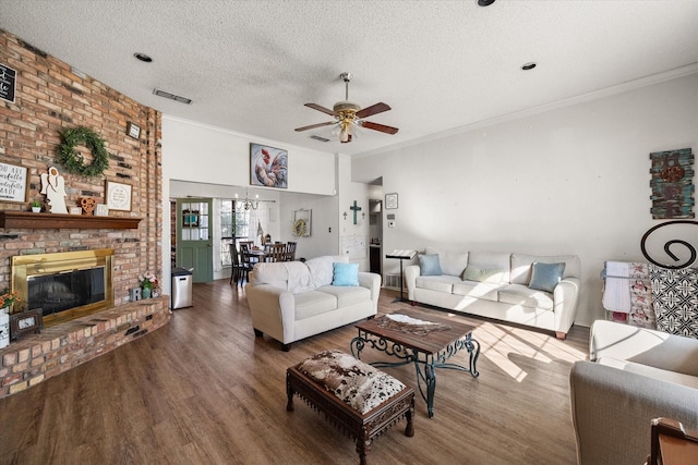 living room with a textured ceiling, ceiling fan, crown molding, a fireplace, and dark hardwood / wood-style floors